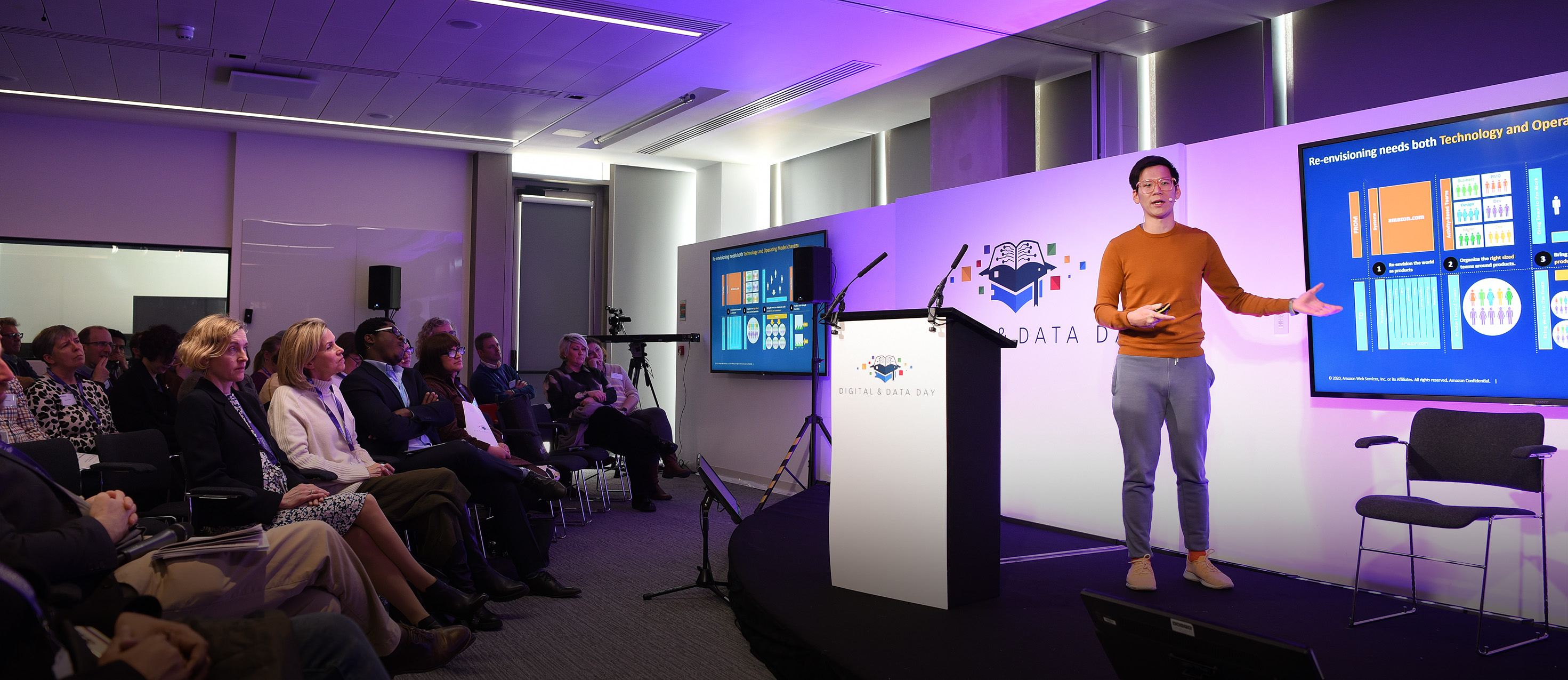 Jason Yung stands on stage delivering his keynote speech to people sitting on chairs in the audience at Digital & Data Day