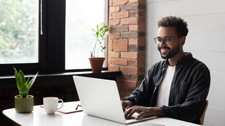smiling man at desk with laptop