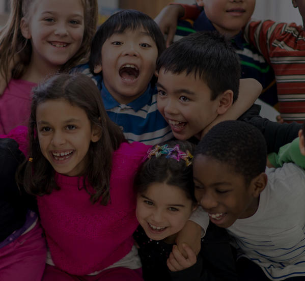 Line of smiling young learners with their arms around each other.