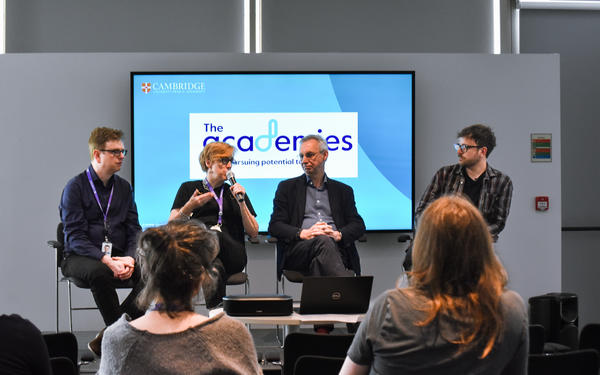 Janet Scotcher holds a microphone while a panel of Nick Raikes, Mark Maddocks, and John Ridpath from Cambridge Spark sit on stage at the launch of the Global Data Academy in front of an audience