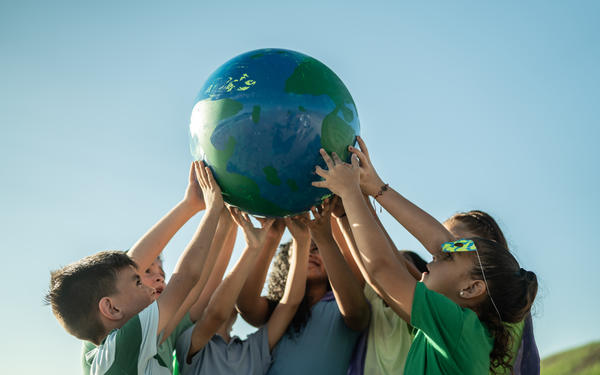 Children collectively holding a globe