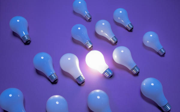 Lightbulbs on a purple background. One lightbulb is lit.