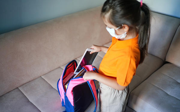 Girl packs tablet in school bag