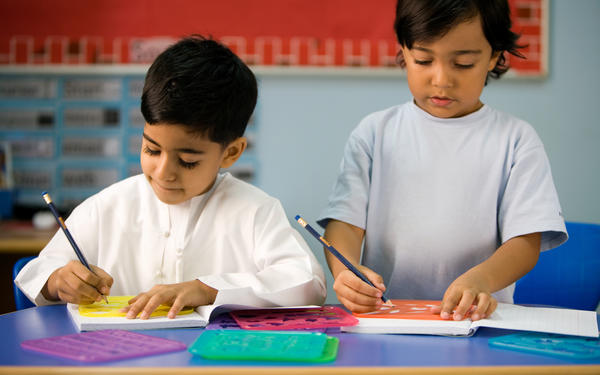 Two children use stencils in a classroom.