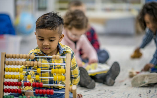 Young child plays with abacus in classroom