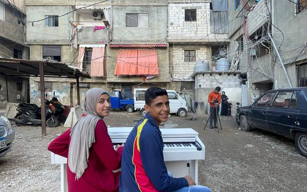 Two children sit at a piano in Shatila refugee camp Lebanon