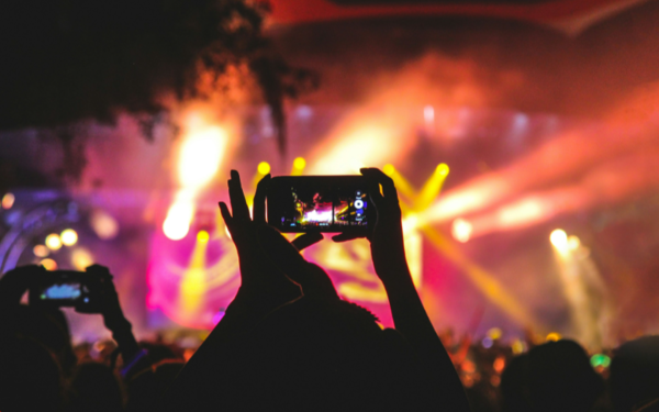 person holding smartphone taking video of a concert near stage with lights during nighttime Photo by Noiseporn on Unsplash