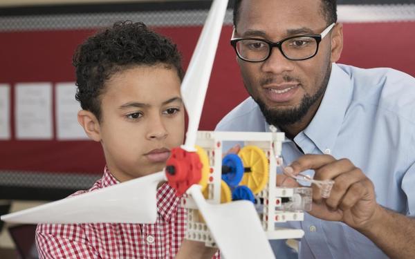 Teacher helping student with model wind turbine 