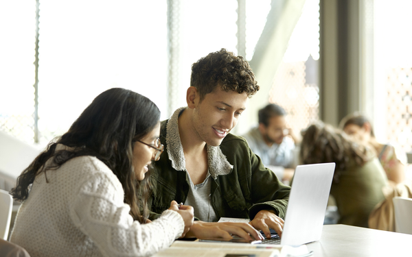 Image of two students looking at laptop screen
