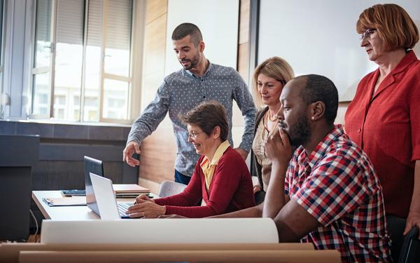 Teachers gathered together looking at a laptop