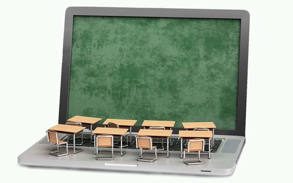 Laptop with exam hall desks and chairs over the keyboard 