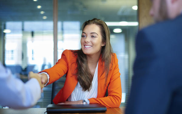 Interviewee sitting at a desk and shaking hands with one of the interviewers