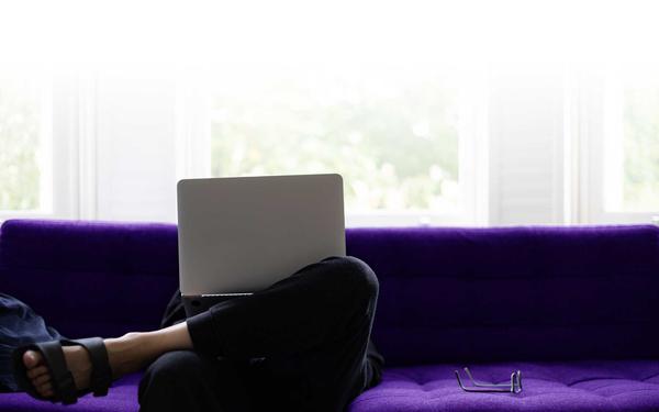 Person working on laptop sat on sofa at home
