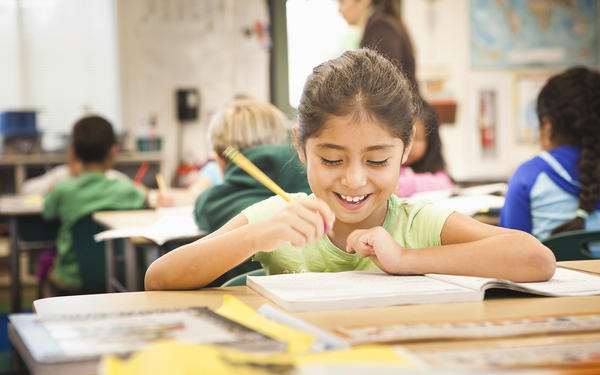 smiling student holding a pencil in class