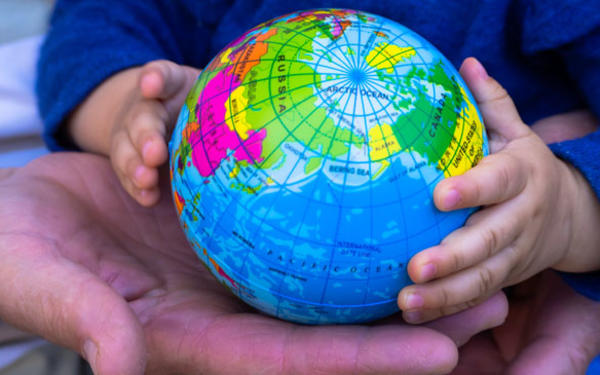 Hands of a child and an adult holding a small globe