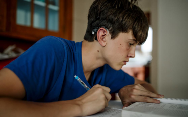 Boy with hearing aid studying