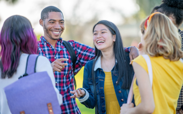 group of 5 students smiling and chatting together