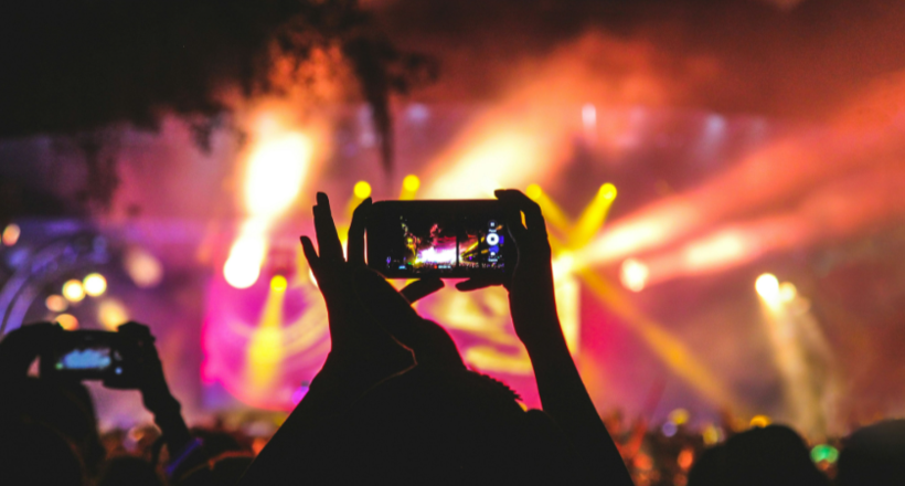 person holding smartphone taking video of a concert near stage with lights during nighttime Photo by Noiseporn on Unsplash