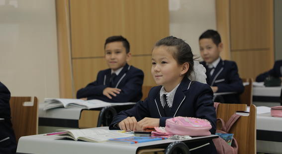 Young children sit at desks in a classroom