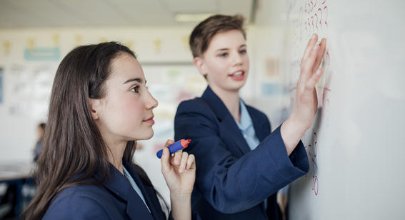 teenage girls correcting answers on the whiteboard.