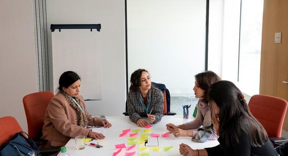 A group of delegates are sitting round a table discussing the post-it notes in front of them