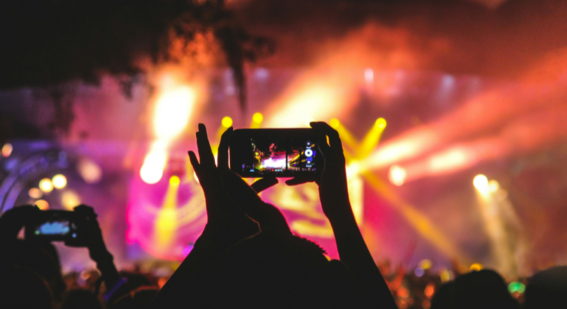 person holding smartphone taking video of a concert near stage with lights during nighttime Photo by Noiseporn on Unsplash