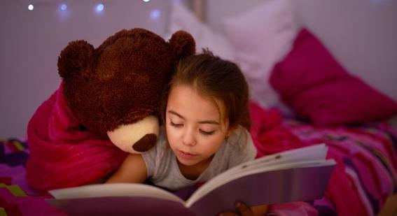 Girl reading book with teddy