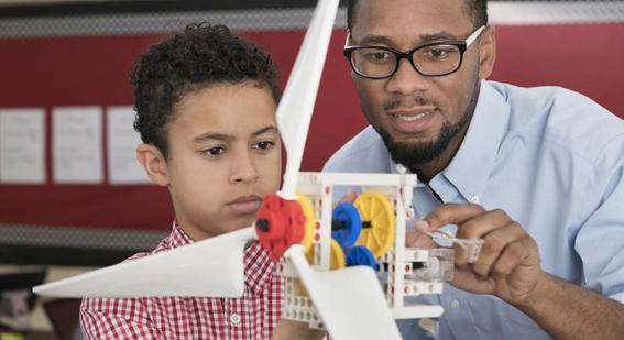 Teacher helping student with model wind turbine 