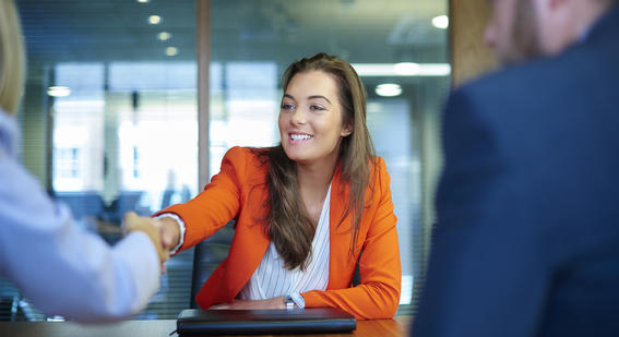 Interviewee sitting at a desk and shaking hands with one of the interviewers