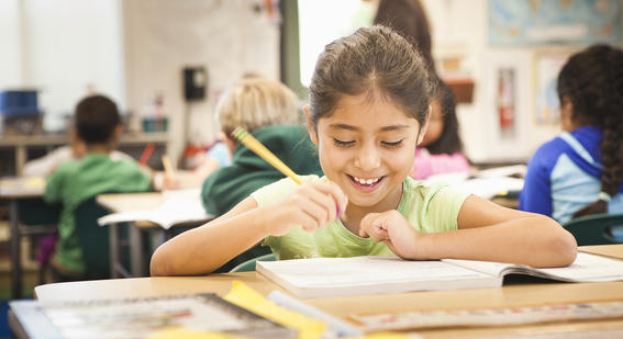 smiling student holding a pencil in class