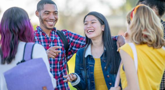 group of 5 students smiling and chatting together