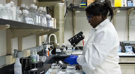 woman wearing white lab coat and blue gloves working in a lab